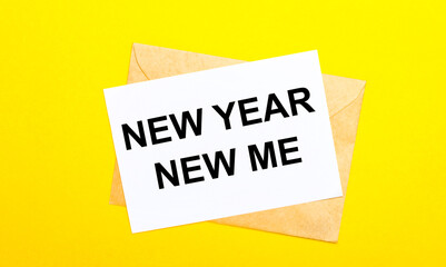 On a yellow background, an envelope and a card with the text NEW YEAR NEW MY. View from above