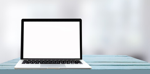 Fototapeta premium Laptop with blank screen on white table with office window view. Home interior or office background