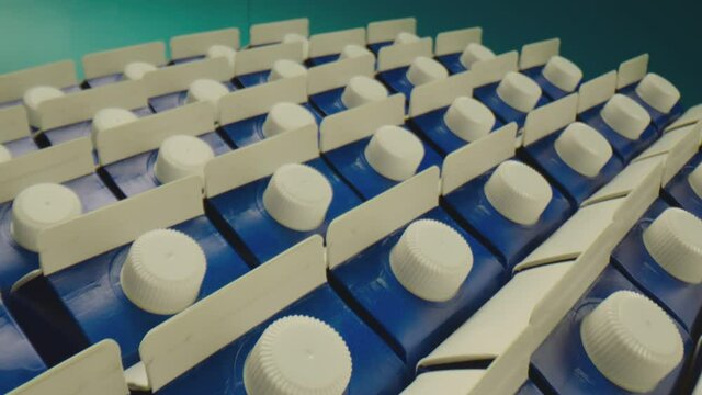 Row of many package with milk on blue isolated background .  Dairy or juice production . Close up Shot on ARRI ALEXA Cinema Camera on slow motion . Closeup Dolly movement . 