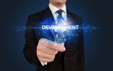 Businessman holding light bulb with DEVELOPMENT inscription, innovative technology concept