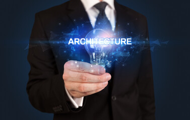 Businessman holding light bulb with ARCHITECTURE inscription, innovative technology concept