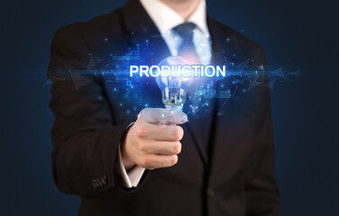 Businessman holding light bulb with PRODUCTION inscription, innovative technology concept