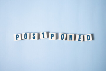 Postponed - words from wooden blocks with letters, postponed concept, top view background.