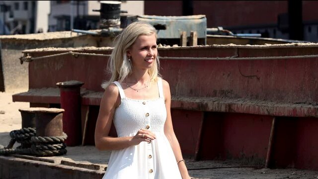 Eine sch&ouml;ne junge Blondine im wei&szlig;en Sommerkleid l&auml;uft im Hafen in Slow Motion. 