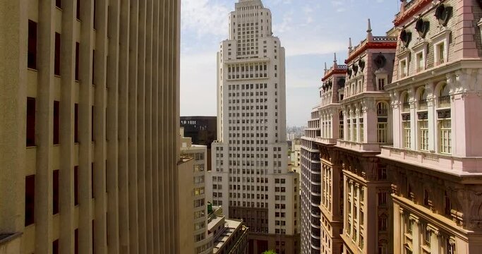 Aerial view in middle of buildings towards the Farol Santander, Banespa Tower, sunny day, in Sao Paulo, Brazil - rising, drone shot