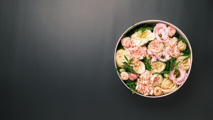 A stylish and delicate flower arrangement in a hat round box on the pink background with copy space. Gift box for 8 March, International Women Day, Mothers Day, St. Valentines Day