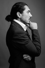 Handsome businessman with mustache wearing suit against gray background