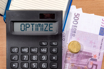 Euro and calculator with the inscription OPTIMIZE monthly expenses. Business concept