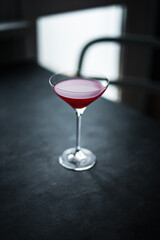 A red raspberry sour cocktail in a beautiful coupe glass, back light, dark and moody photo