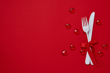 Valentines day background or concept with empty white plate, small heart-shaped plate with small hearts inside and whiteware on scarlet or red background. Banner. Top view with copy space.