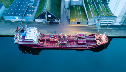 Tanker ship moored at port while unloading oil.