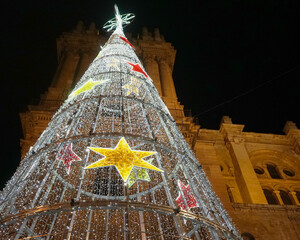 Weihnachten in Malaga, Kegel mit weihnachtlichen Lichtern vor der  mittelalterlichen Kathedrale, Nachtaufnahme