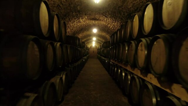 Worker In Wine , Whiskey Or Brandy Warehouse Sorting And Rotating Barrel . Traditional Wine Factory Rolls Barrel . Shot Making By Drone. 4k. Ukraine