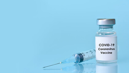 Vaccine in a bottle with a syringe on a blue background.The concept of medicine, healthcare and science.Coronavirus vaccine.Copy space for text.Banner