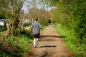 Naklejka na ściany i meble Middle-aged man jogging along the tow path in Hackney, London