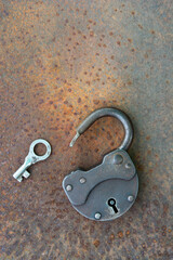 Opened old rusty lock with key lying near on the rusty iron surface. Copy space.looking for problem solution concept. High quality photo