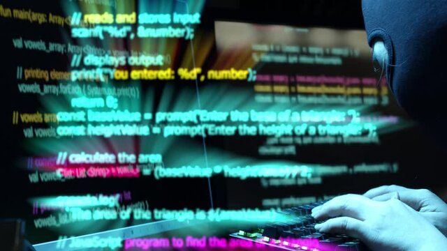 A cyberterrorist types on a keyboard hacks into information systems - glowing code scrolling on screen