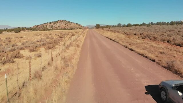 Silver Station Wagon with Bike Rack Smoothly Drives Over Washboard Dirt Road, Low Aerial
