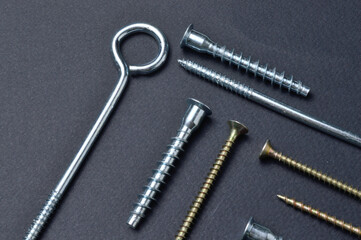 self-tapping screws and various fittings are laid out on a dark background. close-up.