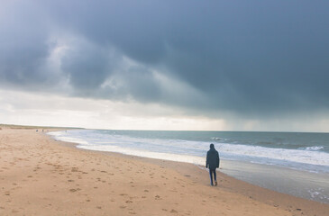 silhouette d'un adolescent seul sur une plage en hiver
