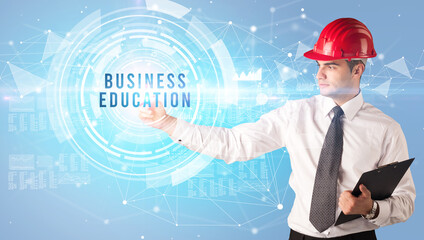 Handsome businessman with helmet drawing BUSINESS EDUCATION inscription, contruction business concept