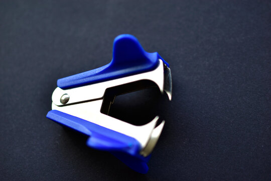 Blue anti-stepler paper clip or expander on a black background