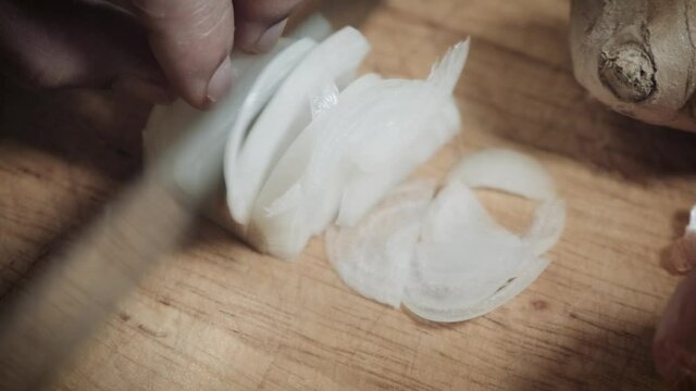 Chef's Hand Rapidly Cutting White Onions On Wooden Chopping Board With Knife. - close up