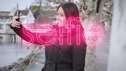 Young female model taking selfies on vacation in small wintry town on the bank of a river. Digital selfie text overlay. - Powered by Adobe