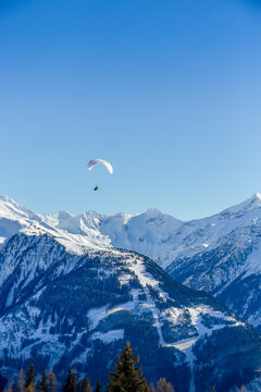 Tandum paragliders float above the rough snow covered mountains below