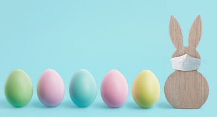 Happy Easter banner or border. Coronavirus protection concept for the Easter holidays. Easter rabbit with a protective mask and colorful eggs. Stay at home Covid-19 concept for Easter with copy space.