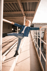 Fototapeta premium Girl in denim clothes dancing hip-hop in the car parking