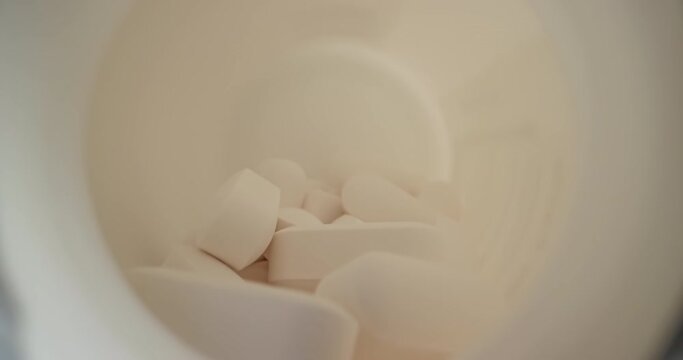 4k 60fps dolly shot of a prescription pill bottle spilled on a table, starting from inside the bottle zooming out