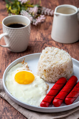 Hotsilog (vertical with coffee and cream)- is a famous Filipino meal that consists of fried rice, egg and hotdogs.