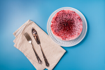 Diet low-calorie raspberry sponge cake with jelly, whipped cream and fresh berries with cutlery on blue background