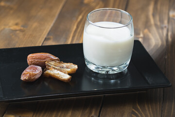 milk and dates in the black plate on a wooden table