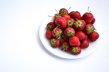 Strawberries on white plate. Freshly picked strawberry. Organic berries on white background. Village garden harvest.