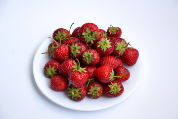 Strawberries on white plate. Freshly picked strawberry. Organic berries on white background. Village garden harvest.