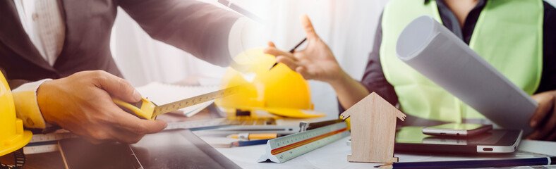 Two colleagues discussing data working and tablet, laptop with on on architectural project at construction site at desk in office
