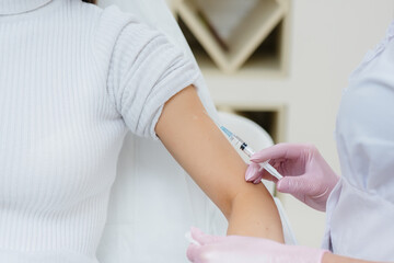 Fototapeta premium Vaccination of a girl against flu and coronavirus infection during a worldwide pandemic. The formation of the immune system and antibodies.