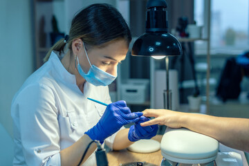 Manicurist doing a manicure in a nail salon, applying varnish on nails