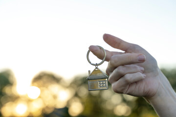 key chain in the form of a house in your hand of buying a home