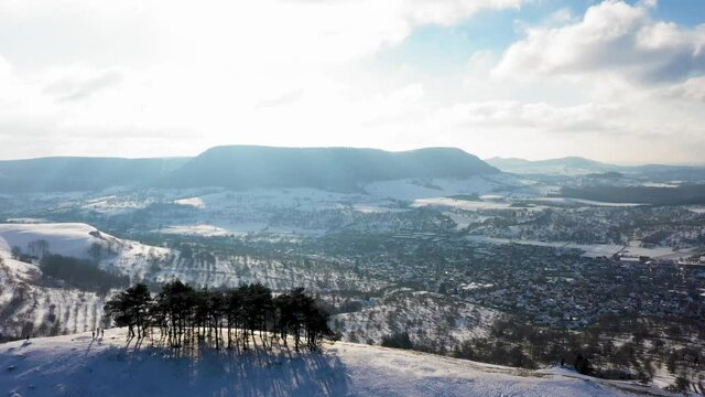 Aerial rotating over winter wonderland with beautiful mountain in the foreground, sun reflecting in camera stunning landscape and Castle Teck in Swabia, Germany.