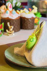 Close-up of a green colored egg and a napkin on a canned table. Bright Easter holiday and decor.