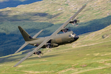 RAF (Royal Air Force) Green camouflage Lockheed C-130 Hercules transport flying low level in the United Kingdom. 