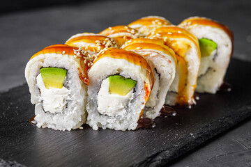 appetizing Philadelphia sushi roll with eel and avocado on a black stone plate