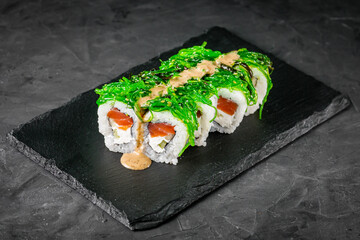 appetizing sushi roll with philadelphia cheese cucumber salmon and chuka on a black stone plate
