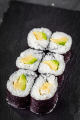 appetizing sushi maki roll avocado on a black stone plate