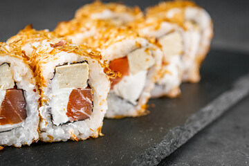 appetizing sushi roll with tuna cheese and tofu on a black stone plate