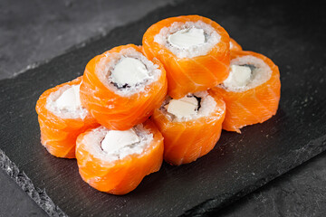 appetizing sushi roll philadelphia with cheese and salmon on a black stone plate