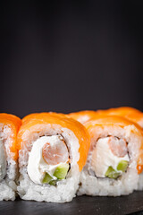 appetizing sushi roll philadelphia with shrimp cheese cucumber and salmon on a black stone plate